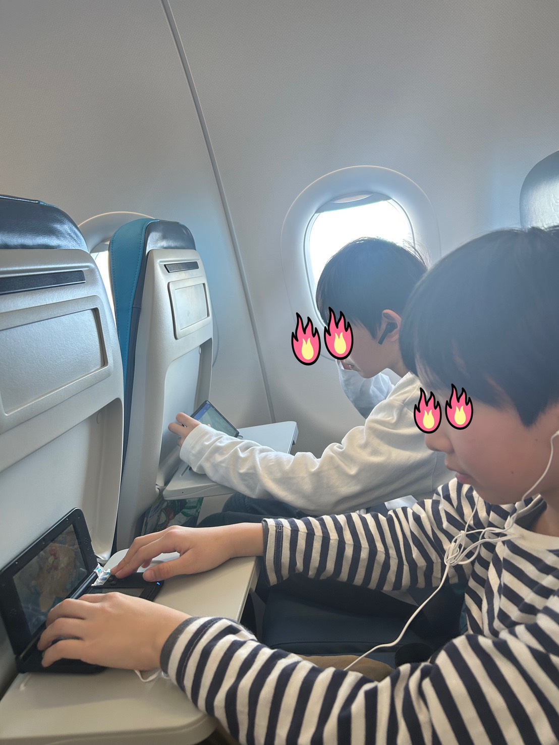 機内でタブレットゲームに夢中になっている子どもたち